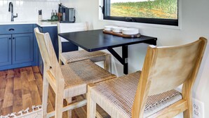 Una cocina moderna con armarios azules, techo de madera y un ventanal con vistas a un campo.