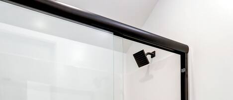Un baño moderno con cabina de ducha de vidrio, inodoro y toallero con toallas.