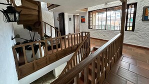 A wooden staircase with a railing leading to a landing. There is a potted plant on the landing and a window with bars on the right. - BLAU HOTEL CAFE (Sopó)