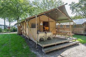 Una terraza de madera con un área de estar cubierta y una mesa de picnic.
