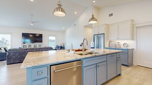 Una cocina moderna con una isla grande, electrodomésticos integrados e iluminación colgante.