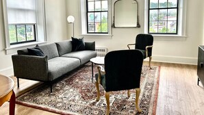 A living room with a grey sofa, a black chair, a round coffee table, and a patterned rug.