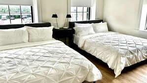 A hotel room with two beds, a nightstand, and a window with blinds.