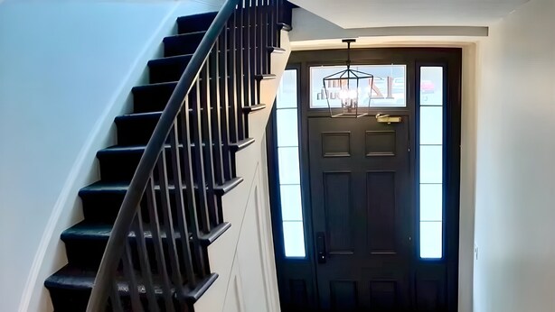 A staircase leading to a dark wooden door with a window above it.