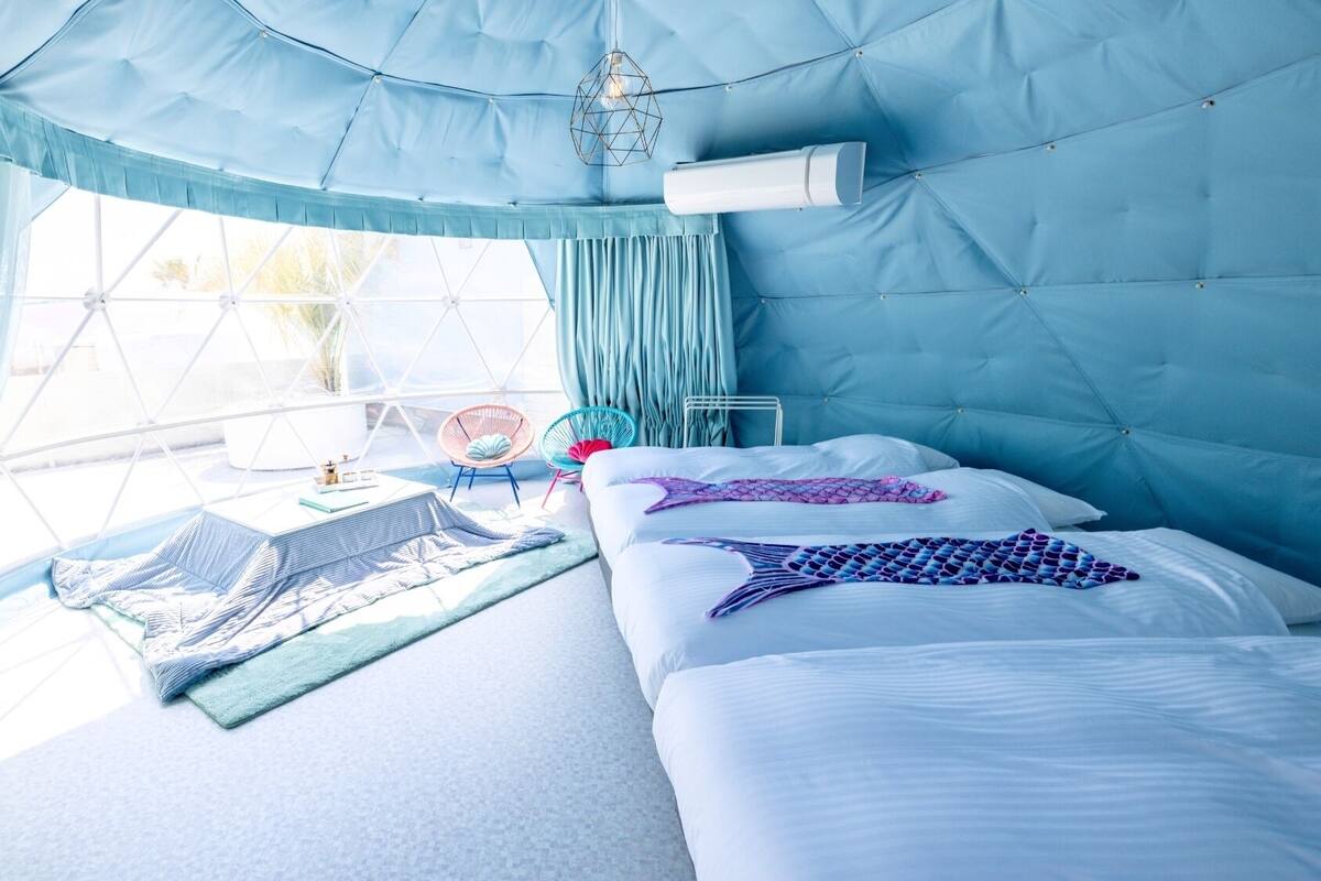 A room with a bed, a chair, a window, and a hanging light fixture.