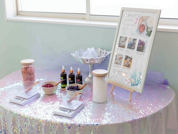 Una mesa con frascos, botellas y una balanza, probablemente para un espacio de spa o belleza hecho en casa.