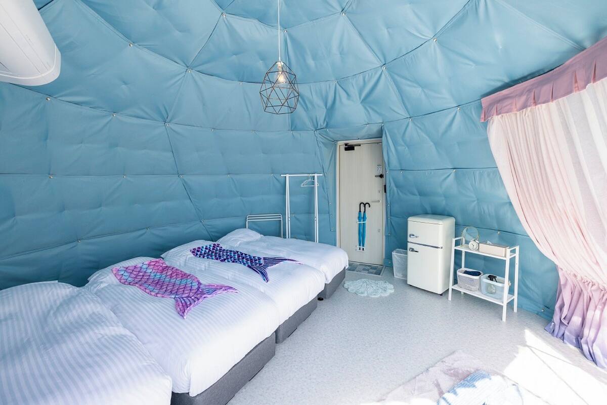 A room with a bed, a small bedside table, a nightstand, a wardrobe, and a hanging light fixture.