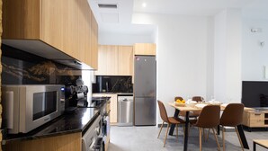 Een moderne keuken met roestvrijstalen apparatuur, houten kasten, en een eethoek met stoelen en een tafel.