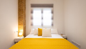 Een hotelkamer met een bed, nachtkastje, lamp en raam met zonwering.