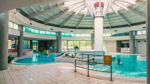 An indoor swimming pool with a high ceiling, multiple levels, and clear glass walls. - Nice Tent Lodge Near a Lake (Mol)