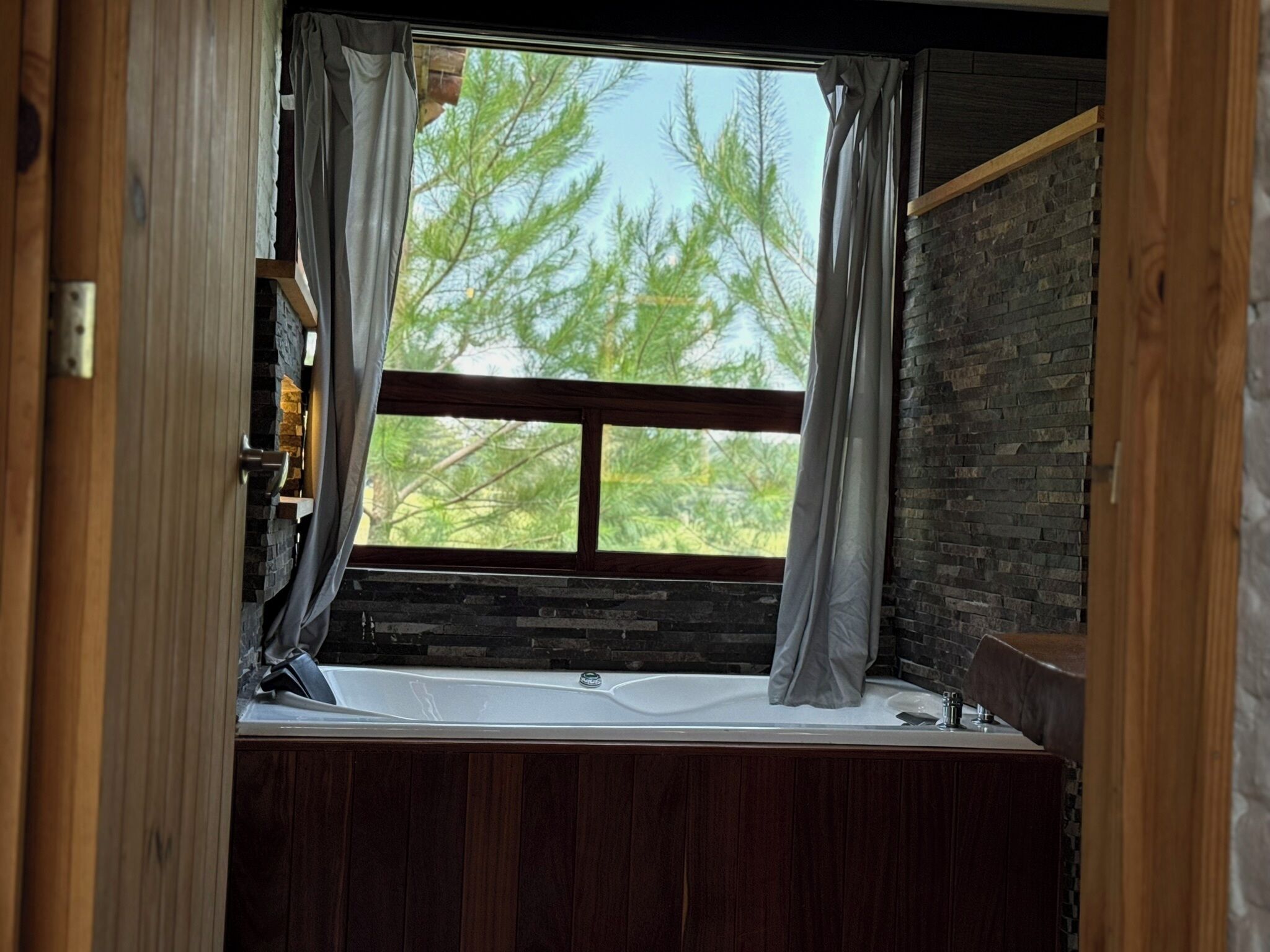 Una habitación con un ventanal grande, paredes de madera y un banco.
