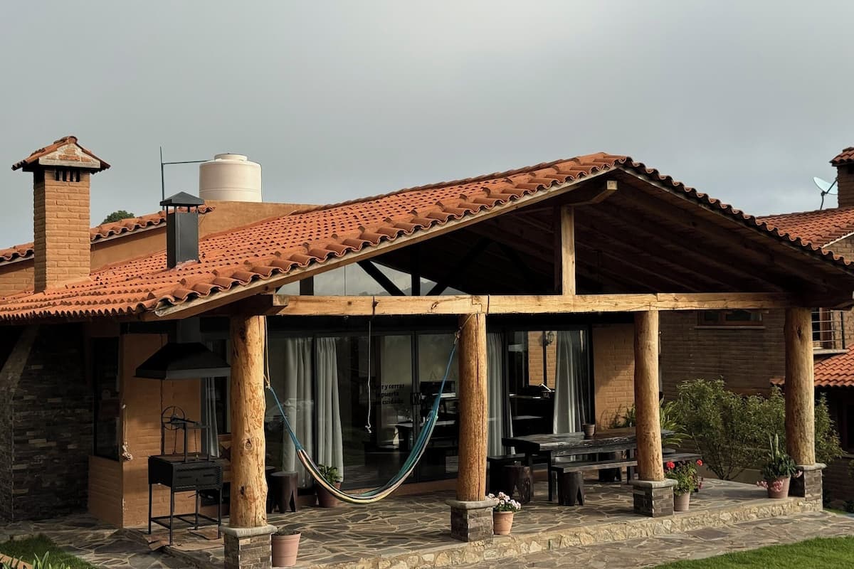 Une terrasse couverte, aménagée avec du mobilier d’extérieur, un hamac et des plantes en pot.