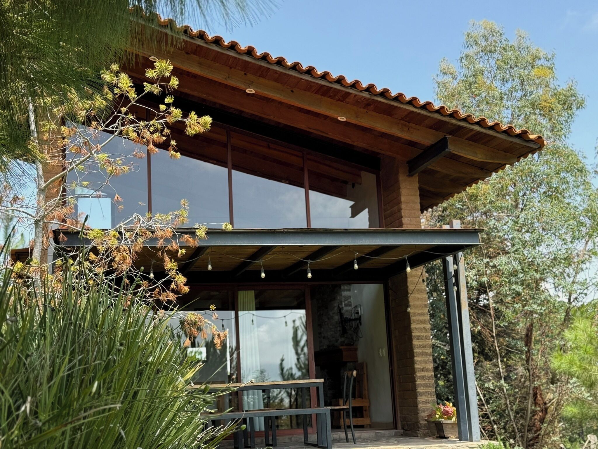 A modern house with a large glass window, a wooden deck, and a patio area.