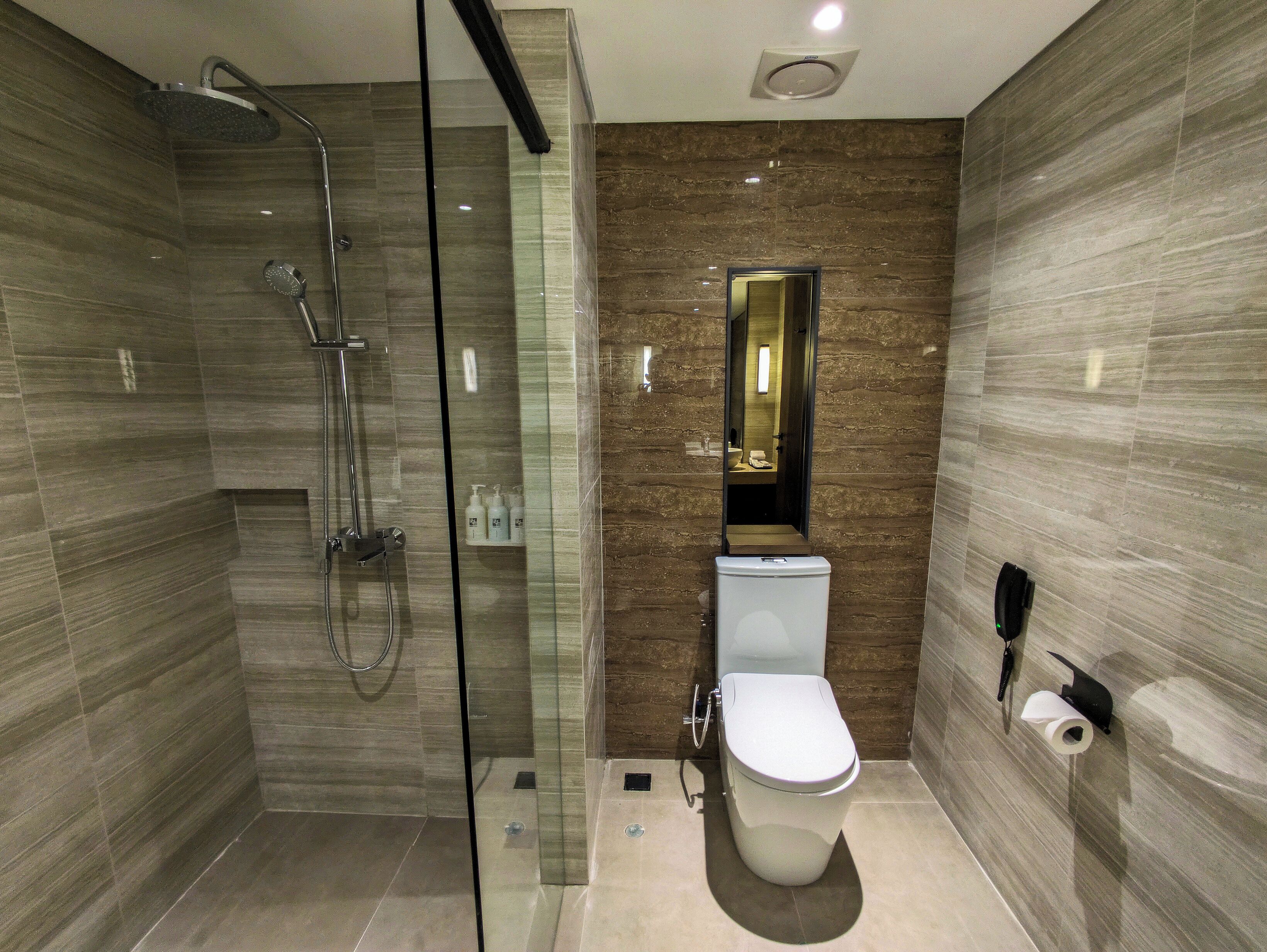 Un baño moderno con ducha de vidrio, inodoro y espejo.