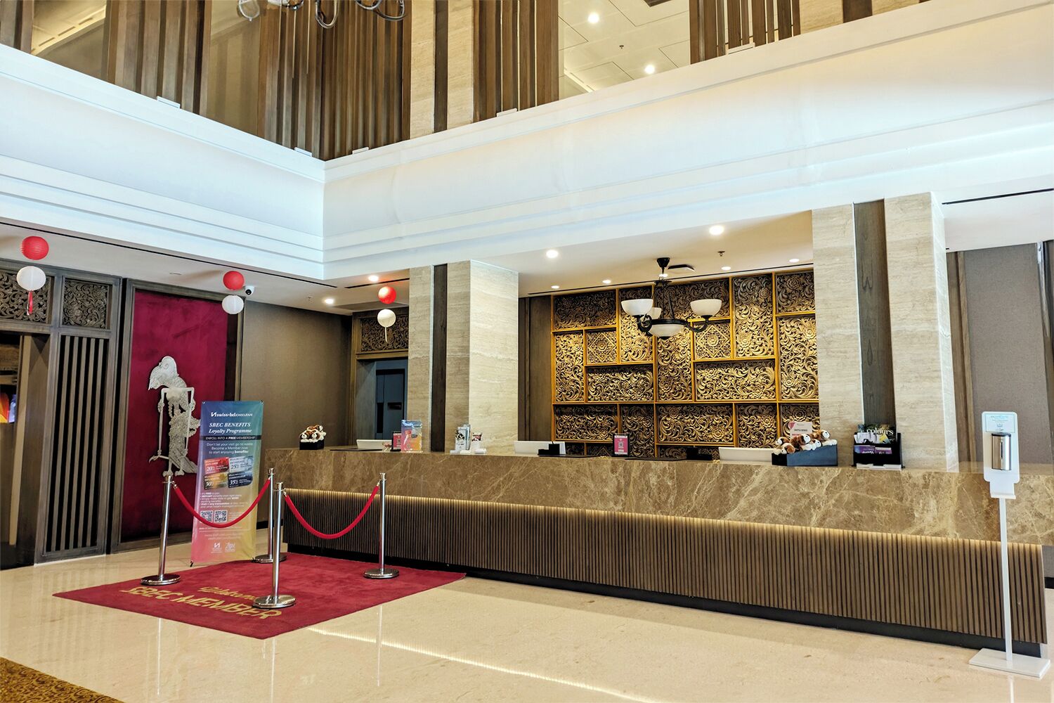 A hotel reception area with a marble counter, a red carpet, and a decorative wall.