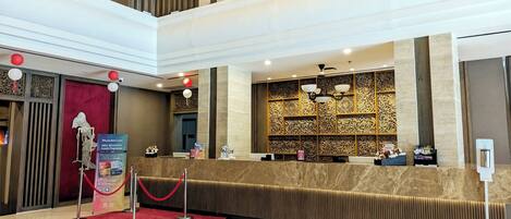 A hotel reception area with a marble counter, a red carpet, and a decorative wall.