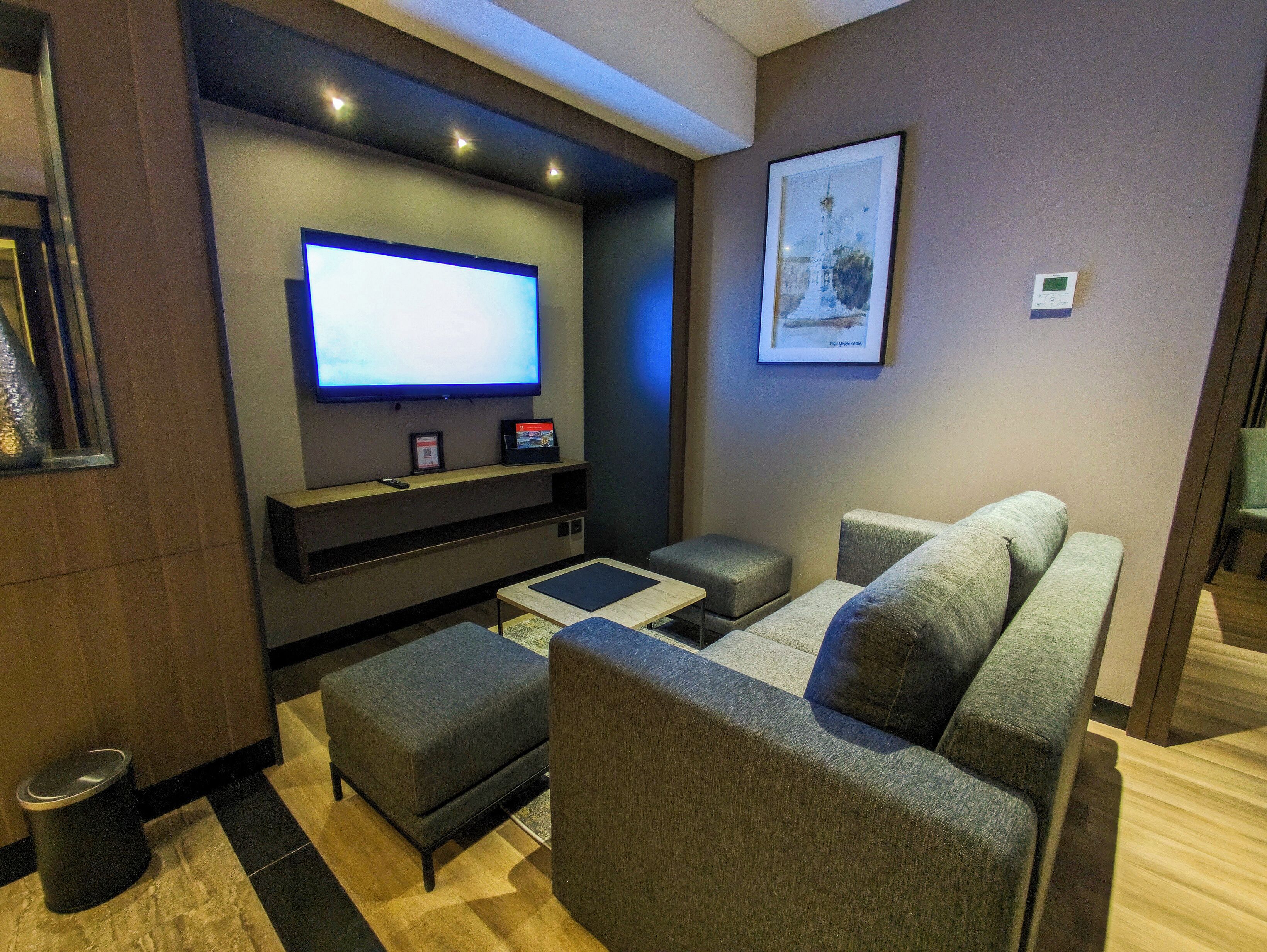 Una sala de estar moderna con un televisor de pantalla plana, sofás grises y una pequeña mesa de centro.