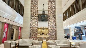 Un hall con mostrador de recepción, zona de estar y paneles decorativos.