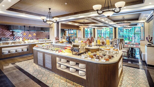 Una barra de desayuno moderna con diversas opciones de comida y un espacio de estar con mesas y sillas.