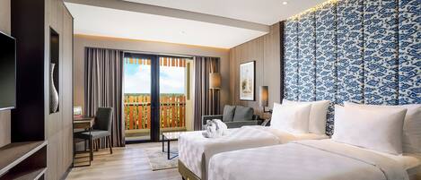 A hotel room with two beds, a TV, a desk, and a balcony with a view.