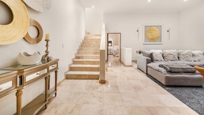 A modern living room with a staircase, a sofa, and a console table. - Villa Cactus (Cabo San Lucas)