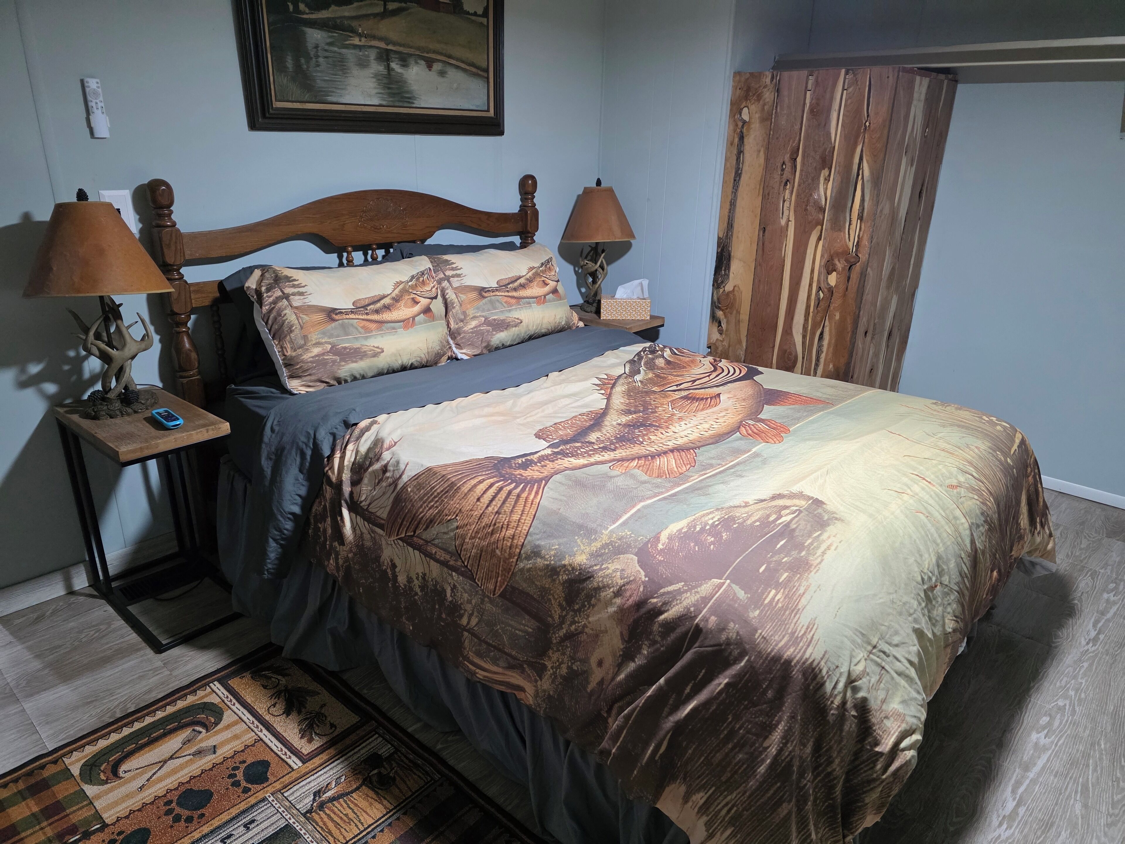 Een slaapkamer met een houten bedframe, een nachtkastje met een lamp en een bijzettafeltje met een afstandsbediening.