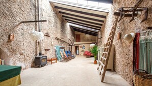 A rustic interior with a stone wall, a fireplace, a ladder, and a wooden table. - 'Ca'n Pont' with Mountain Views, Private Pool and Wi-Fi (Illes Balears)