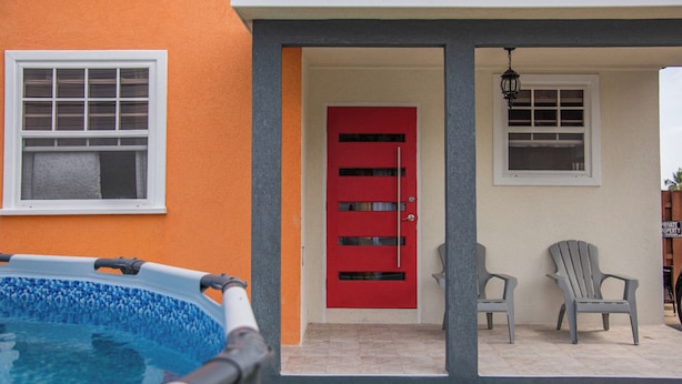 A swimming pool, a red door, and two Adirondack chairs outside a building. - Anrym #1 - by Zenbreak (St. Lawrence Gap)