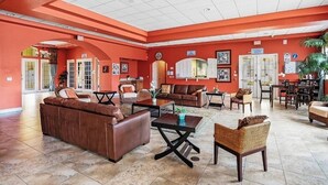 A spacious lobby with a red and white color scheme, featuring leather sofas, a coffee table, and a wicker chair.