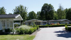 A row of white mobile homes with a paved driveway and landscaped gardens. - Nice Safari Tent Near Recreation Area (Noord-Scharwoude)