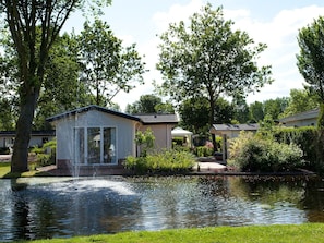Eine friedliche Uferlandschaft mit einem kleinen Pavillon und einem Springbrunnen.