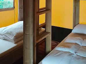 Ein Schlafsaalzimmer mit zwei Einzelbetten, Holzbettgestellen und einem Fenster.