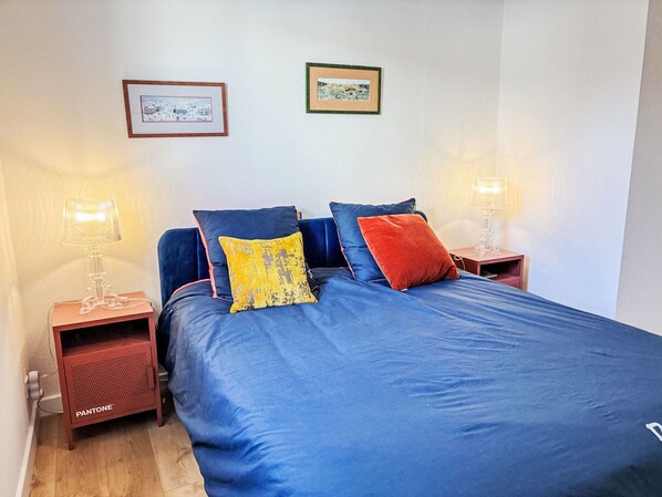 A bedroom with a large bed, two bedside tables, and two wall-mounted lamps.