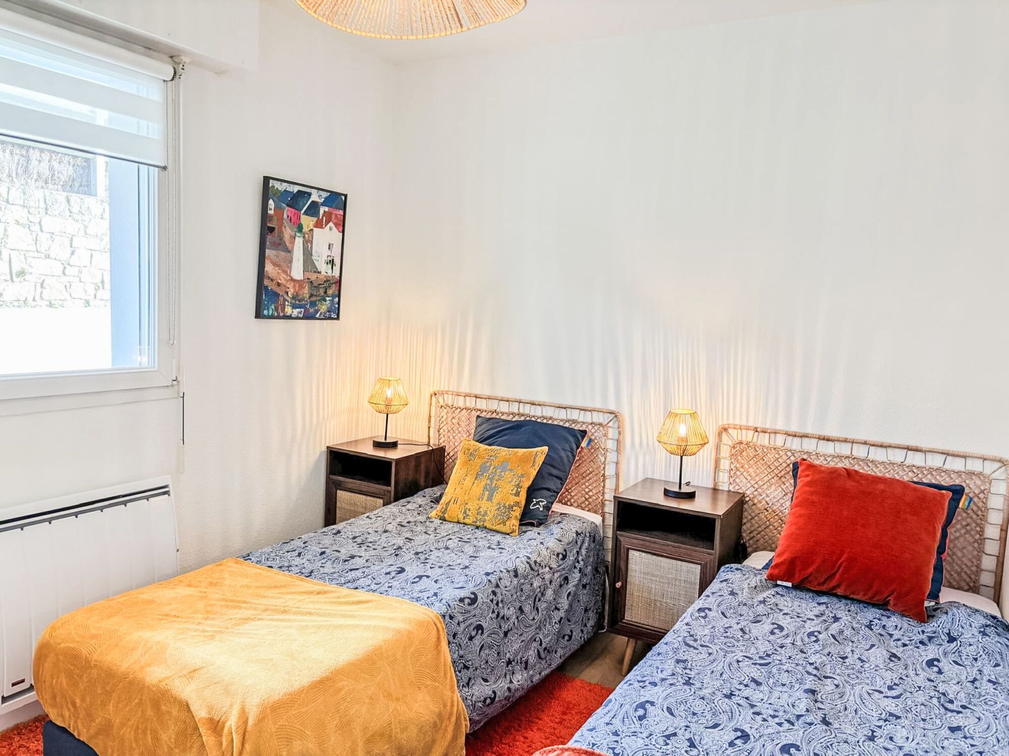 Una camera da letto con due letti singoli, una finestra, un termosifone e un quadro appeso al muro.