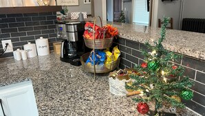 A kitchen with a coffee maker, sugar and coffee containers, snack baskets, and a small Christmas tree. - Lovely 2 BR 2BA, Close to Mayo and trails (Rochester)