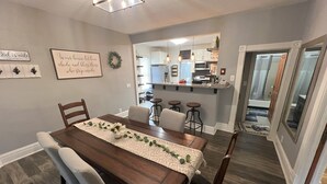 A dining area with a wooden table, chairs, and a decorative runner. A kitchen is visible in the background. - Lovely 2 BR 2BA, Close to Mayo and trails (Rochester)