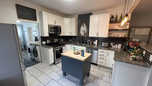 A modern kitchen with white cabinets, a central island, stainless steel appliances, and a decorative Christmas tree. - Lovely 2 BR 2BA, Close to Mayo and trails (Rochester)