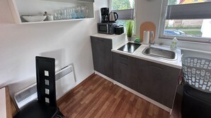 Eine kleine Küche mit Spüle, einer Kaffeemaschine und einer Wanduhr.
