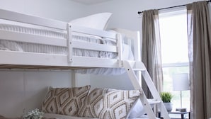 Habitació amb literes, una taula d'estudi i una finestra amb cortines.