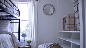 A bunk bed room with a small table, a mirror, and a window with curtains. - Cozy 2-bedroom mobile home in lovely Encampment with AC, WiFi (Encampment)