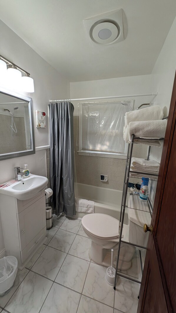 A bathroom with a toilet, sink, shower, and a towel rack.