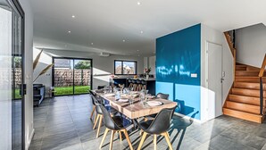 A modern dining area with a large table, black chairs, and a blue accent wall. - Les Voiles by Interhome (Quiberon)
