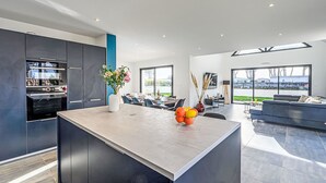 A modern kitchen with built-in appliances, a central island, and a dining area with a view. - Les Voiles by Interhome (Quiberon)