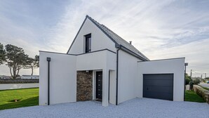 A modern house with a sloped roof, a stone accent wall, and a garage. - Les Voiles by Interhome (Quiberon)