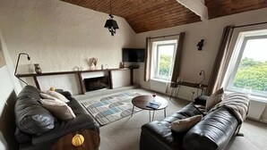 A modern living room with a fireplace, leather sofas, a coffee table, and a TV mounted on the wall. - 2 Bed-Sleeps 4-Sea View-Pet Friendly-Parking (Llanelli)