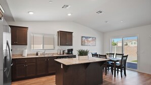Une cuisine moderne avec des meubles de couleur bois foncé, un plan de travail en granit et un îlot central.