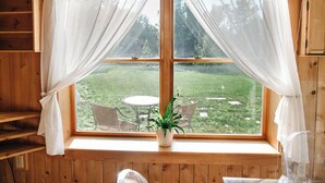 Une pièce dotée d’une grande fenêtre, d’une plante en pot et d’une table avec des chaises à l’extérieur.