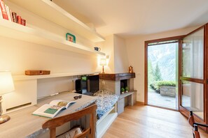 Una habitación acogedora con cama, un rincón de lectura con lámpara, chimenea y vistas a un paisaje montañoso.