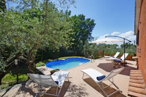 A backyard with a swimming pool, lounge chairs, and a pergola with umbrellas.