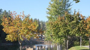 A gazebo by a lake with autumn foliage, a clear sky, and a building in the background. - Impressive Deck - 301B (Kelowna)